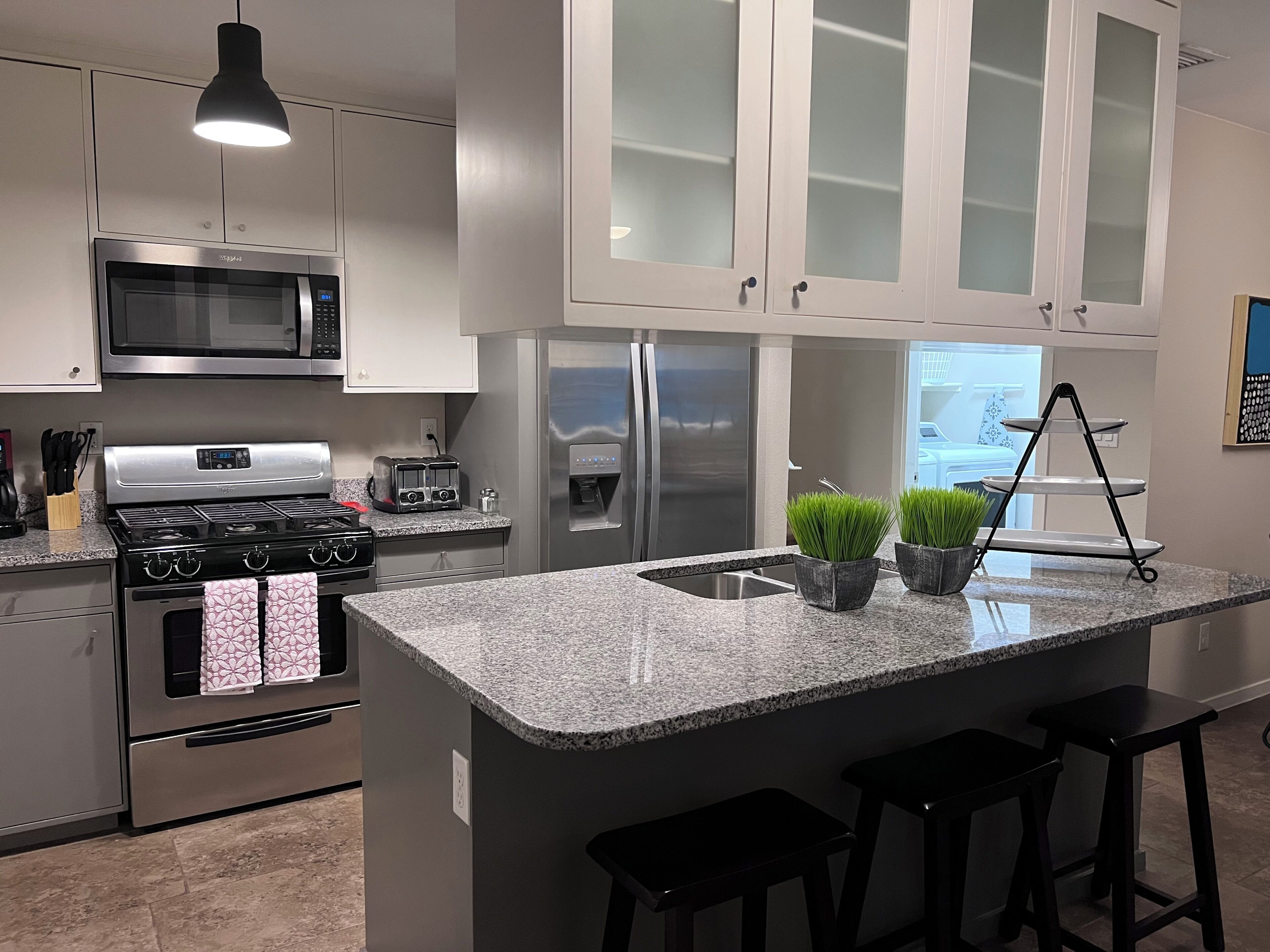 A modern kitchen with stainless steel appliances, granite countertops, and a central island with bar stools.
