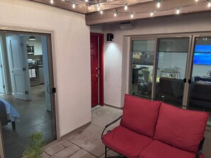 Ein roter Sessel in einem Zimmer mit einer Glastür, die auf einen Balkon führt.