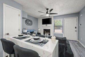 A dining area with a white marble table, black chairs, and a ceiling fan. - Walk to AT&T Stadium | Modern 2BR, Free Parking (Arlington)