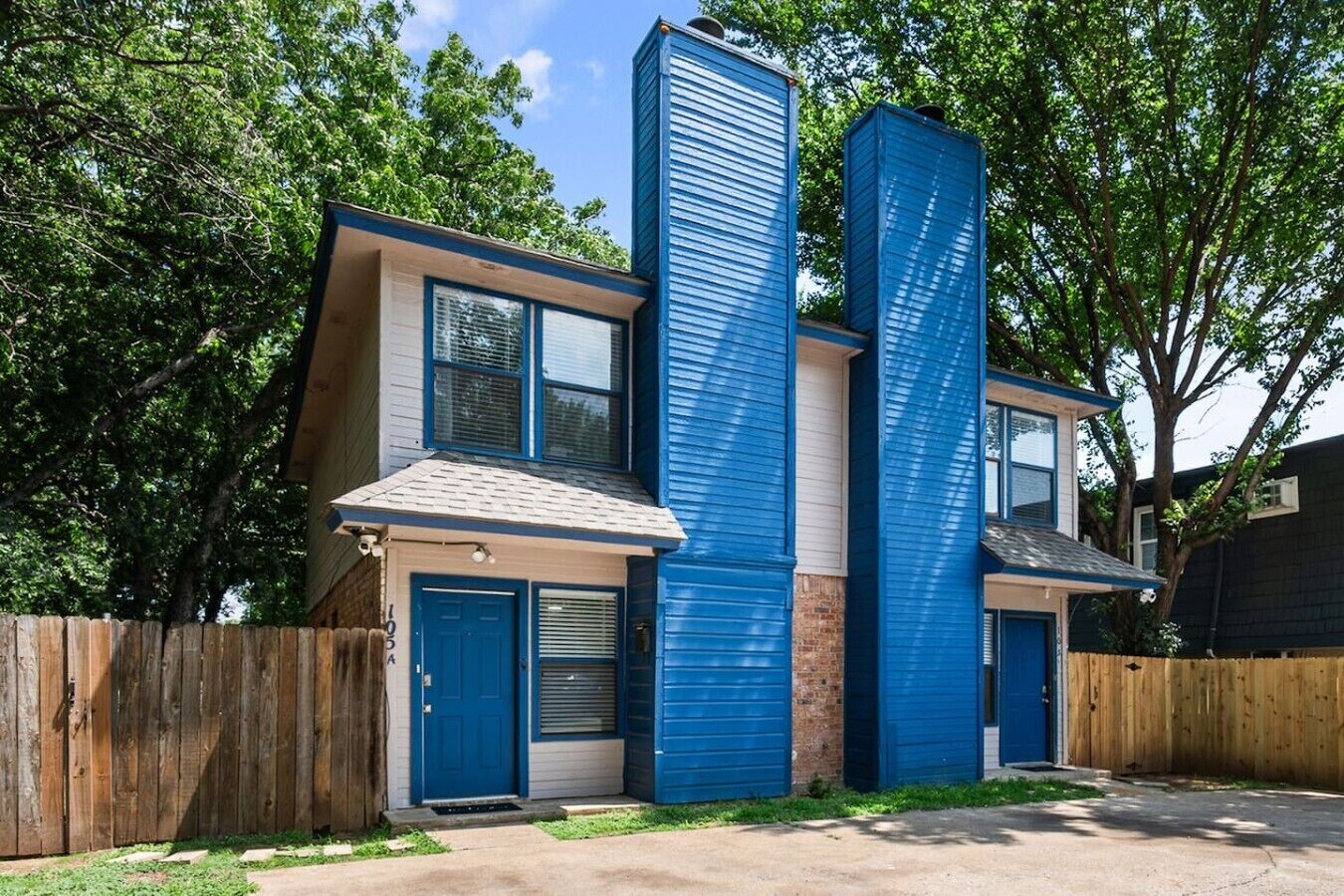 A two-story residential building with a blue exterior, a front door, and a garage door.