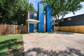 A residential property with a two-story house, a front garage, and a fenced backyard. - Walk to AT&T Stadium | Modern 2BR, Free Parking (Arlington)