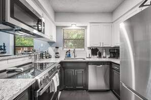 A compact kitchen with a built-in oven, a dishwasher, and a stainless steel refrigerator.