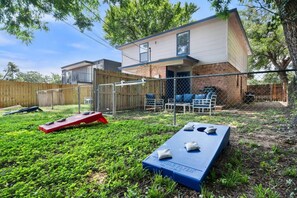 A backyard with a trampoline, a red and blue flying disc, and a fenced area with outdoor furniture. - Game Day Modern 2BR | Steps to AT&T & Globe Life (Arlington)
