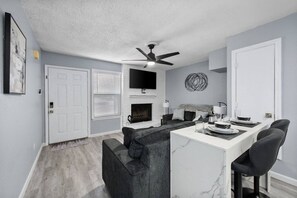 A modern kitchen with a white countertop, black chairs, and a ceiling fan. - Game Day Modern 2BR | Steps to AT&T & Globe Life (Arlington)