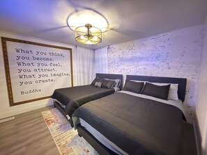 Une chambre avec deux lits, un luminaire au plafond et une citation inspirante sur le mur.