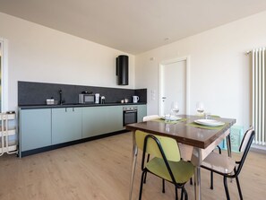 A modern kitchen with a dining area, featuring a microwave, kettle, and oven. - Serracapelli by Interhome (Neive)