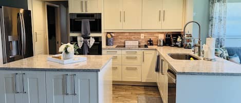 A modern kitchen with a central island, stainless steel appliances, and a sign reading 'Meals & Memories.'