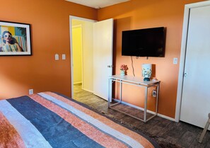 Ein Schlafzimmer mit Bett, Nachttisch, Fernseher und einer Tür.