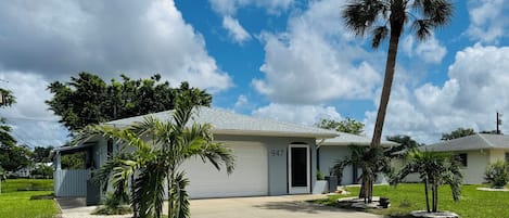 Casa de una planta con garaje, número 947, rodeada de césped cuidado y palmeras.
