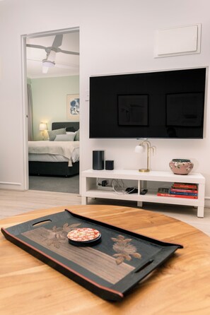 Une chambre à coucher moderne avec un lit, une table de chevet et un téléviseur fixé au mur.