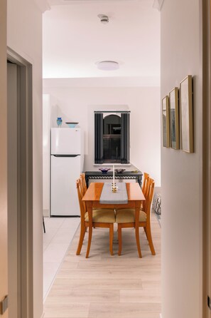 Une cuisine compacte avec un coin repas, comprenant un réfrigérateur blanc, un four à micro-ondes et une table à manger avec des chaises.