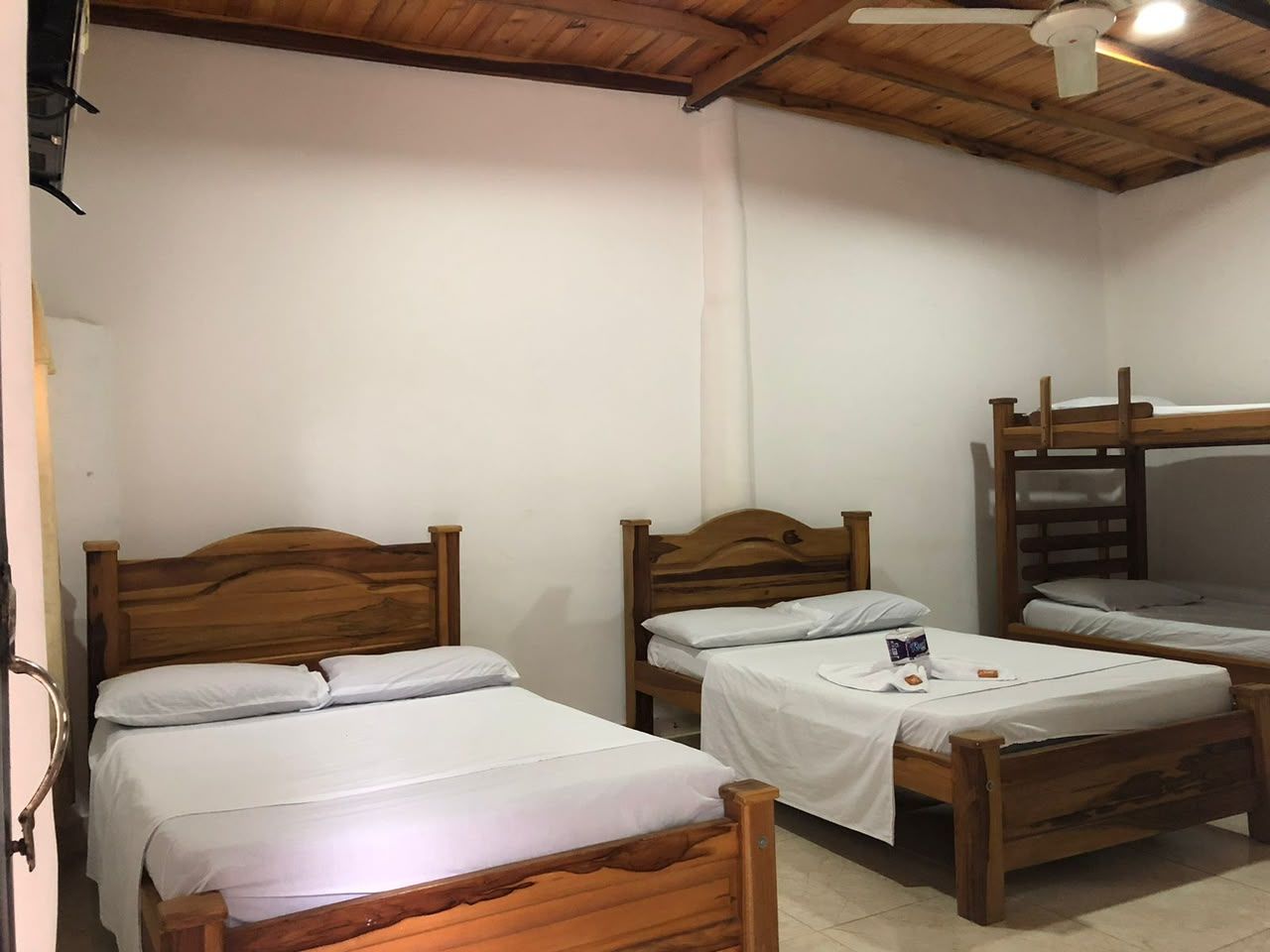 A room with three wooden beds, a bunk bed, and a ceiling fan.