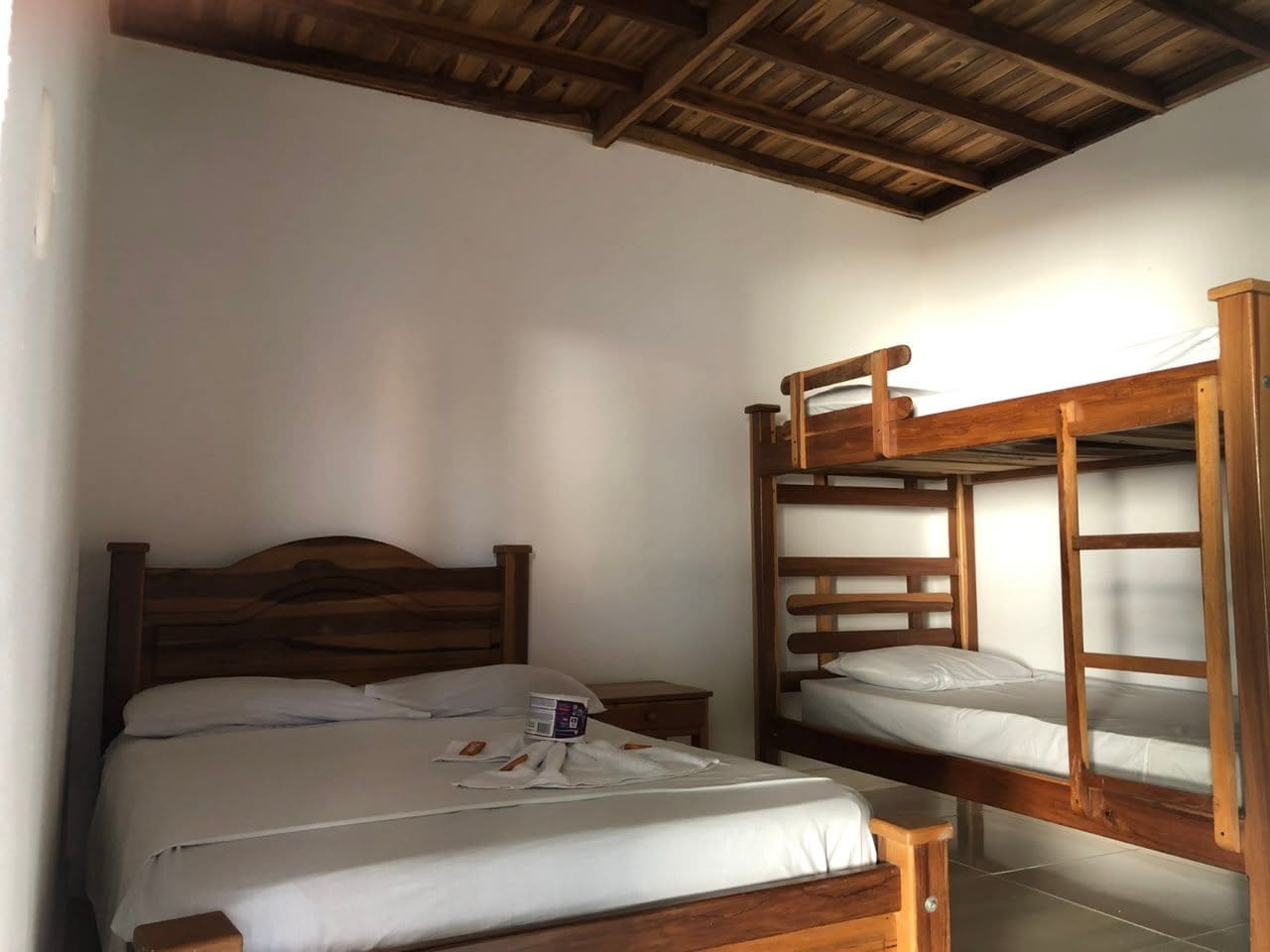 A room with a single bed, a wooden bunk bed, and a nightstand with a book.