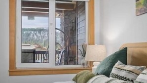 A bedroom with a bed, a window, a lamp, and a view of the outdoors. - Ski-In King Executive Resort Suite w/ Mtn Views, Pool & Garage! (Mammoth Lakes)