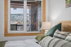 A bedroom with a bed, a window, a lamp, and a view of the outdoors. - Ski-In King Executive Resort Suite w/ Mtn Views, Pool & Garage! (Mammoth Lakes)