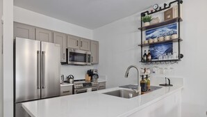 A modern kitchen with stainless steel appliances, a white countertop, and a built-in sink. - Ski-In King Executive Resort Suite w/ Mtn Views, Pool & Garage! (Mammoth Lakes)