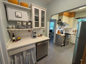 Eine Küche mit weißen Schränken, einer Kaffeemaschine und einem Kühlschrank.