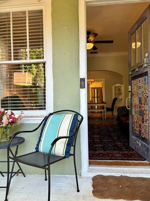 A chair with a striped cushion outside a door, a window with blinds, and a patterned door. - The Natty - Charming 3BR Bungalow Near UF, The Swamp & Law School (Gainesville)