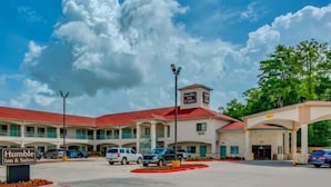 A hotel with a red roof, multiple parking spaces, and a sign for 'Humble Inn & Suites.'