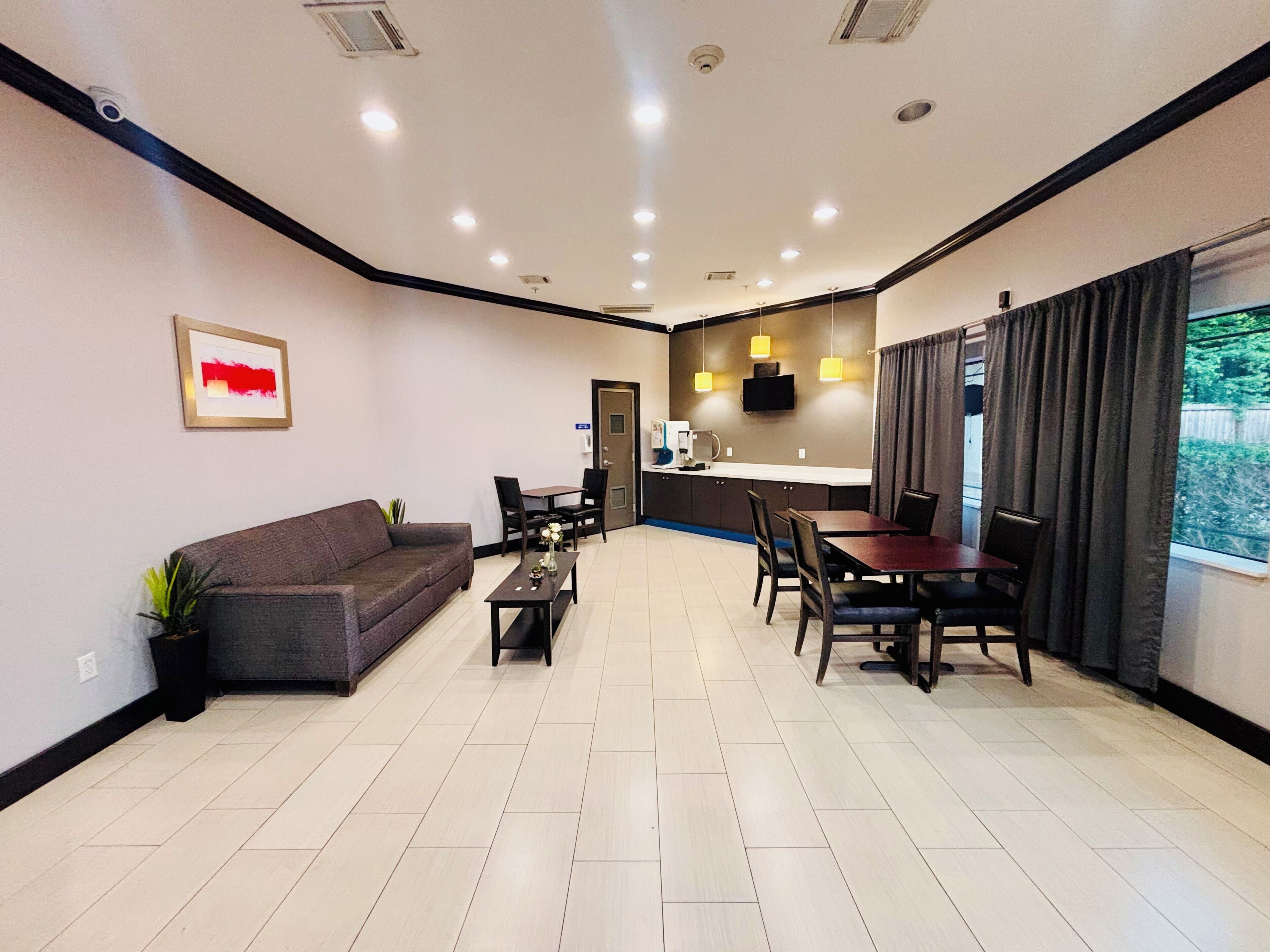Hotelkamer met een bank, eettafel, stoelen, koffiehoek en een aan de muur bevestigde televisie.