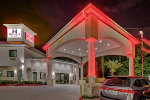 A hotel with a prominent entrance, a covered outdoor area, and a parking lot. - Humble Inn & Suites (Humble)