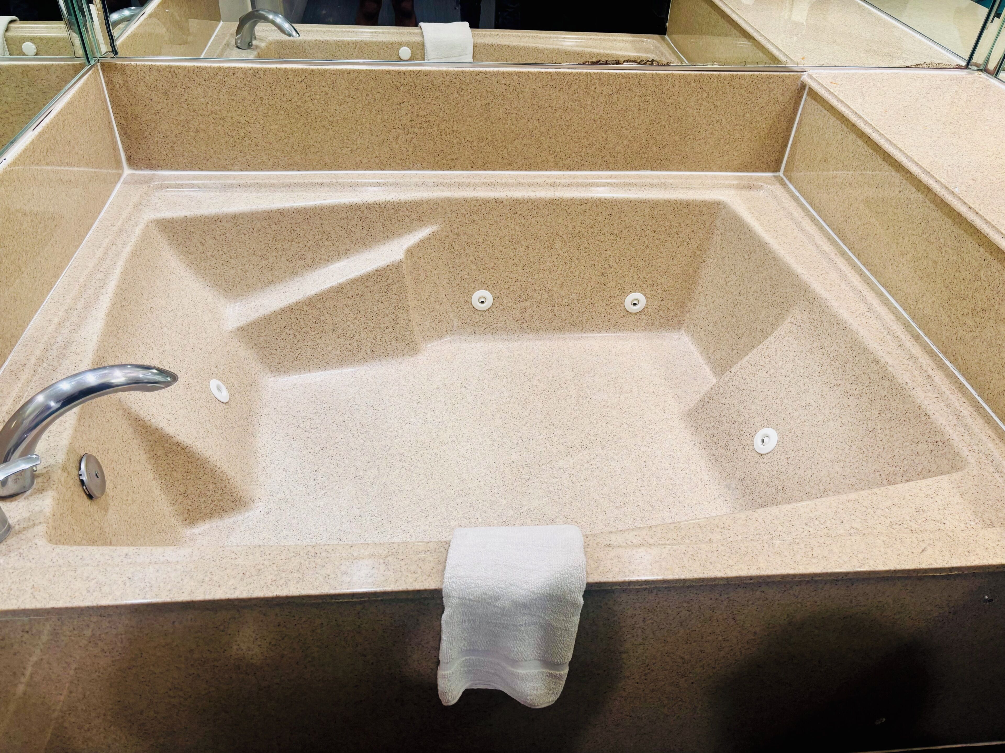Una bañera rectangular con un solo grifo y dos desagües.