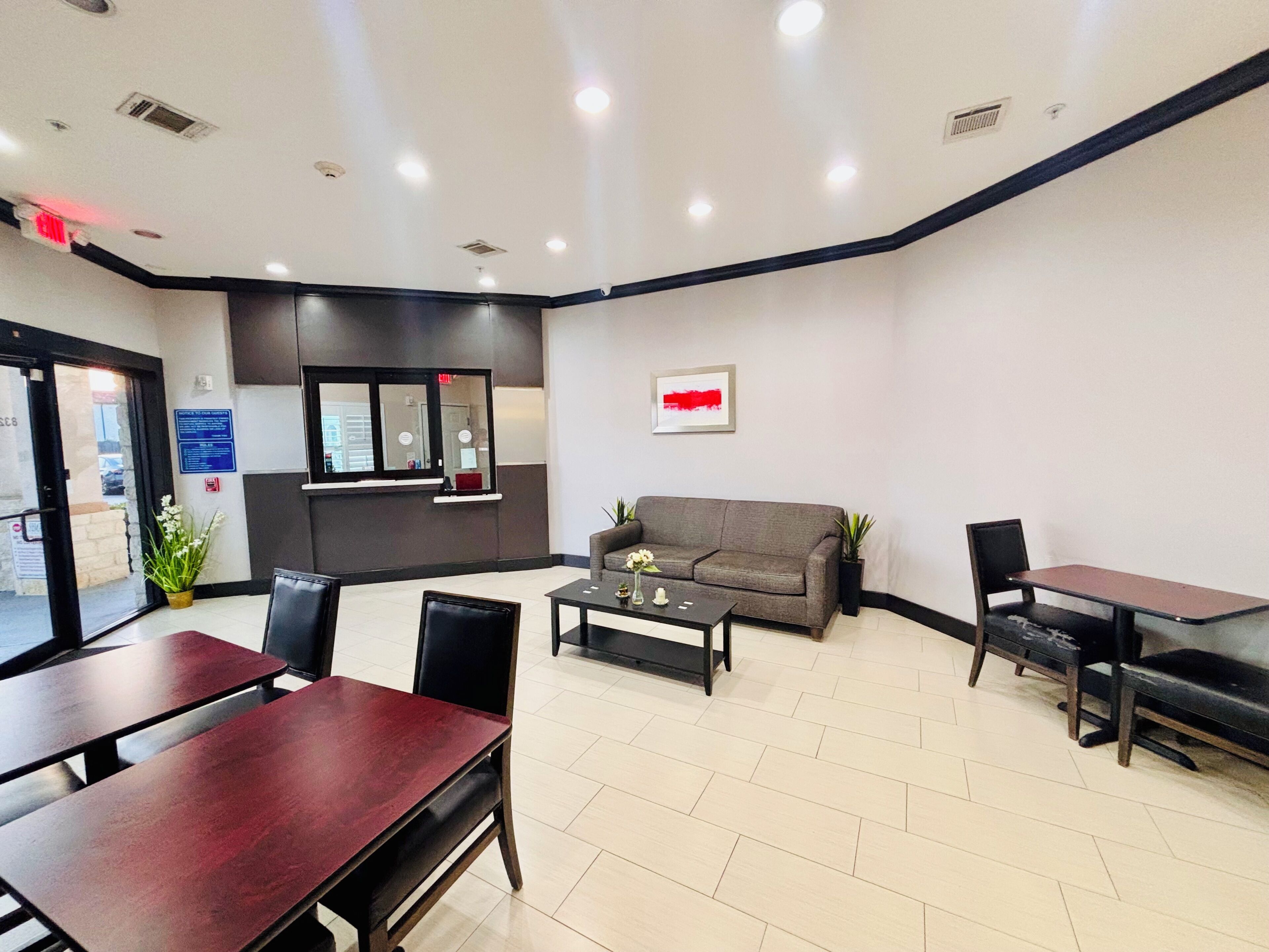A reception area with a sofa, a coffee table, and a desk. There is a window with a view of the outside.