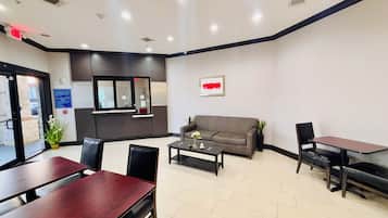 A reception area with a sofa, a coffee table, and a desk. There is a window with a view of the outside.