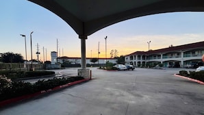 A parking lot with a building in the background, a clear sky, and a sunset.