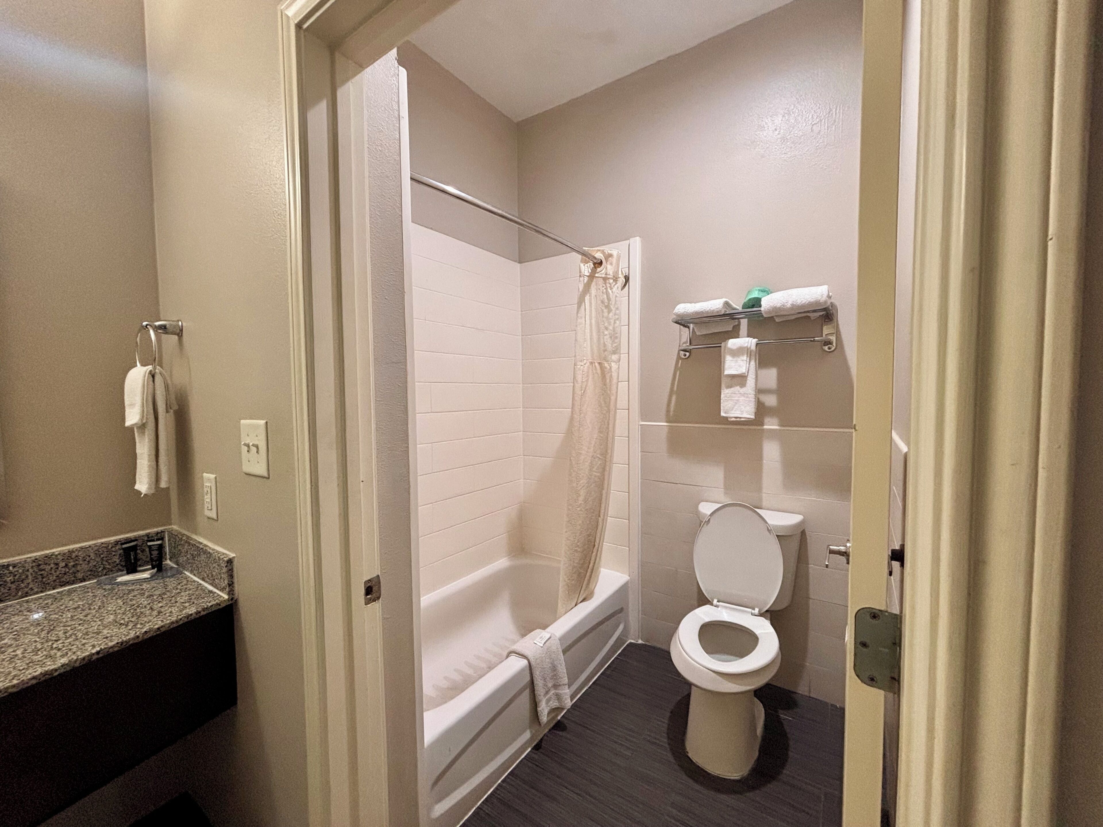 A bathroom with a bathtub, toilet, and a shower curtain.