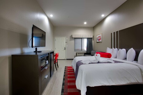 Een hotelkamer met een bed, een bureau, een televisie en een deur.