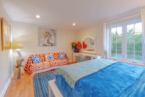 Ein Schlafzimmer mit Bett, Sofa, Schreibtisch, Fenster und einem Bild an der Wand.