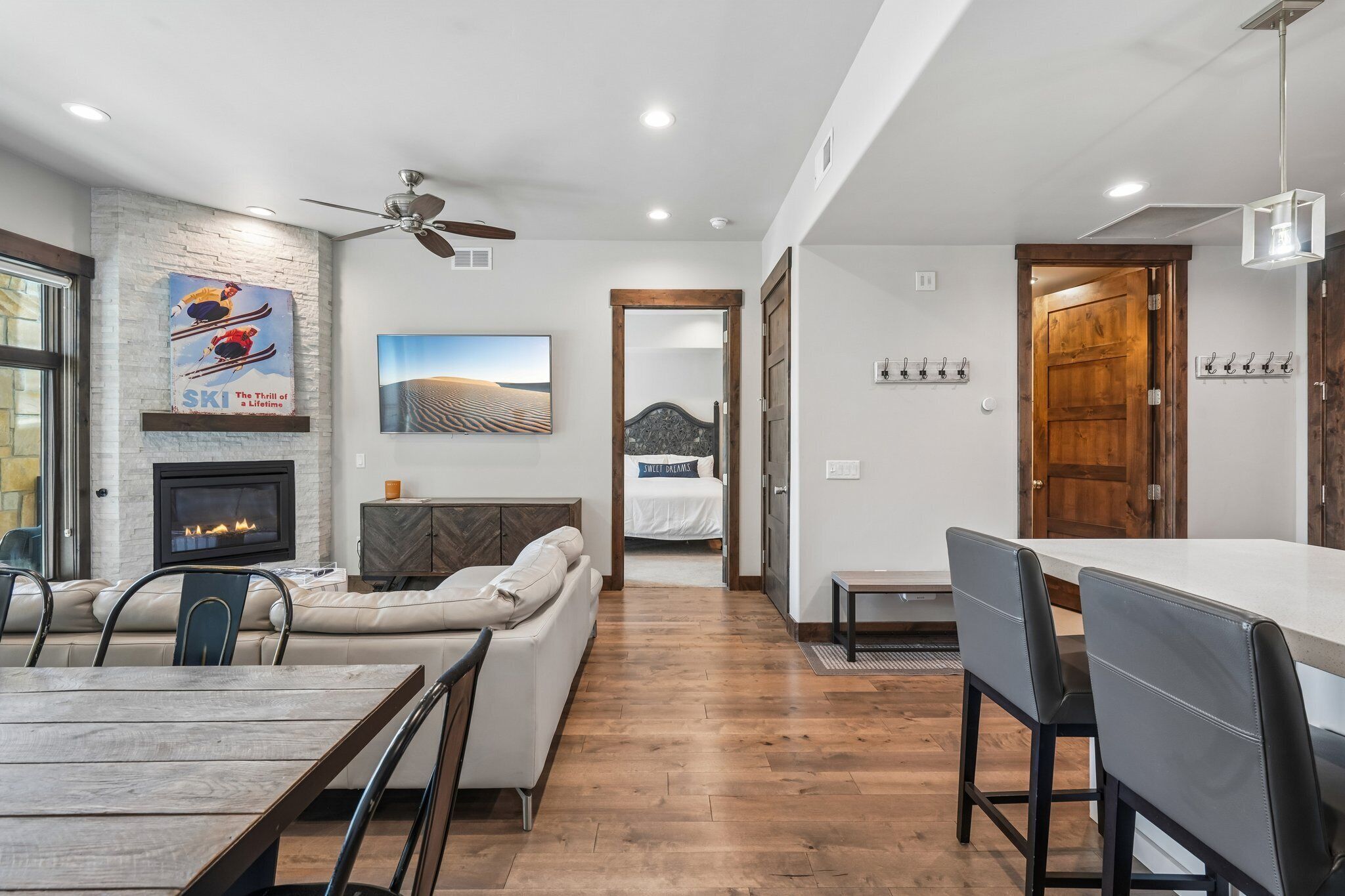 A modern living room with a fireplace, a dining area with a wooden table, and a kitchen with a wooden door.