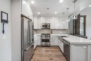 Una cocina moderna con electrodomésticos de acero inoxidable, armarios blancos y suelo de madera.