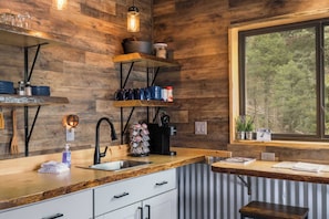 A modern kitchen with wooden walls, a large window, and built-in shelves.