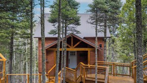 A wooden cabin with a wooden deck and stairs, surrounded by tall trees. - RidgeWalk Lodge and Treehouse - Sleeps 17, Views (Angel Fire)