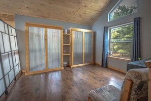 A room with wooden floors, a large window with curtains, and a view of trees. - RidgeWalk Lodge and Treehouse - Sleeps 17, Views (Angel Fire)