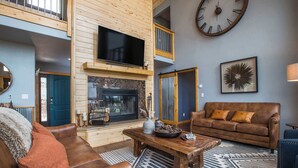 A living room with a fireplace, a large clock, and a sofa. - RidgeWalk Lodge and Treehouse - Sleeps 17, Views (Angel Fire)