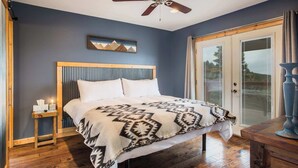 A bedroom with a bed, a nightstand, a ceiling fan, and a window with blinds. - RidgeWalk Lodge and Treehouse - Sleeps 17, Views (Angel Fire)