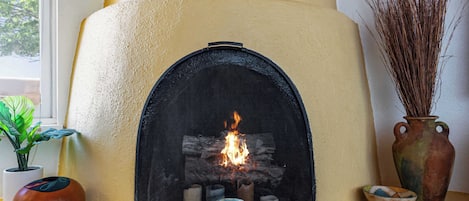 Una chimenea con fuego, rodeada de elementos decorativos y plantas.