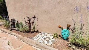 A garden with a stone pathway, a cactus, and metal sculptures. - Casa de Colores - Adobe Retreat, Dog-Friendly, AC (Santa Fe)