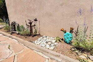 A garden with a stone pathway, a cactus, and metal sculptures. - Casa de Colores - Adobe Retreat, Dog-Friendly, AC (Santa Fe)
