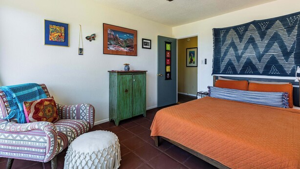 A bedroom with a bed, a chair, a cabinet, and a ceiling fan. - Casa de Colores - Adobe Retreat, Dog-Friendly, AC (Santa Fe)