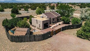 A single-story house with a fenced yard, a patio with outdoor furniture, and a clear view of the surrounding landscape. - Casa de Colores - Adobe Retreat, Dog-Friendly, AC (Santa Fe)