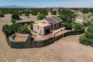 A single-story house with a fenced yard, a patio with outdoor furniture, and a clear view of the surrounding landscape. - Casa de Colores - Adobe Retreat, Dog-Friendly, AC (Santa Fe)