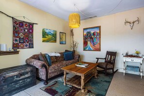 Ein gemütliches Wohnzimmer mit einem gemusterten Sofa, einem Holztisch und einem rustikalen Sessel.