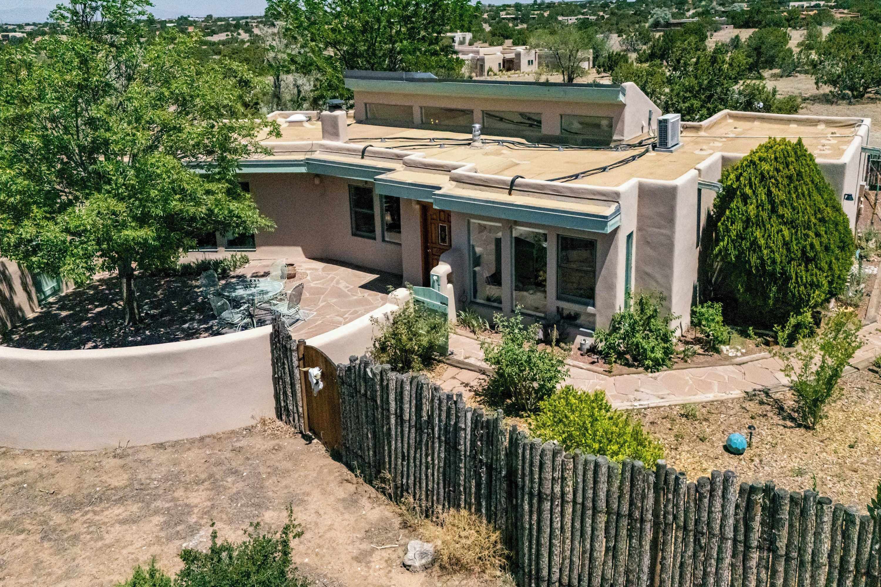 A modern house with a flat roof, large windows, and a fenced yard.