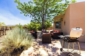 An outdoor patio with wicker furniture, a grill, and a view of the surrounding landscape. - Casa de Colores - Adobe Retreat, Dog-Friendly, AC (Santa Fe)