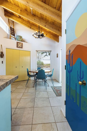 A dining area with a wooden ceiling, a chandelier, and a view through a window. - Casa de Colores - Adobe Retreat, Dog-Friendly, AC (Santa Fe)