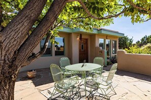 A patio with a round table and chairs, a wooden door, and a view of the sky. - Casa de Colores - Adobe Retreat, Dog-Friendly, AC (Santa Fe)